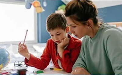 mother sitting next to her son, tutoring him with his schoolwork