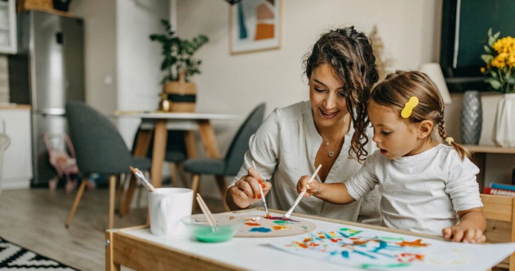 Mother and young daughter painting together.
